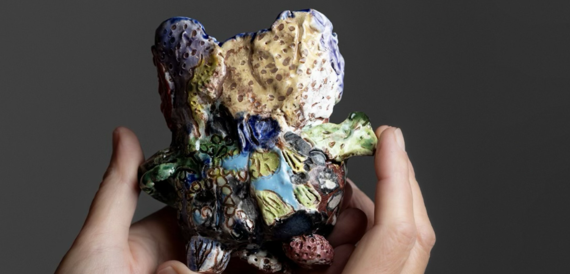 Two hands holding an abstract ceramic sculpture